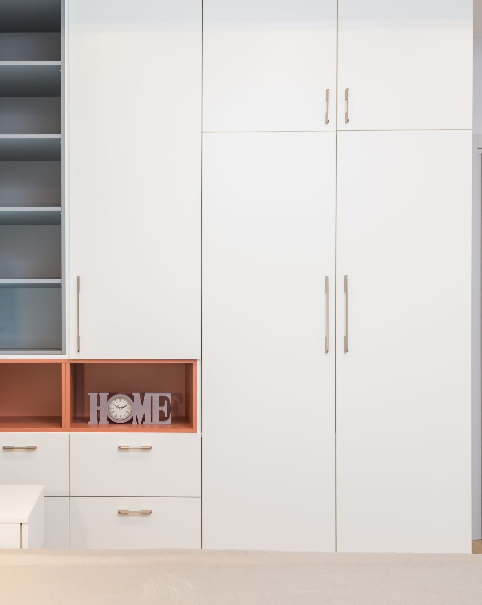 White wardrobe placed near comfortable bed with cushions and bedside table in modern apartment
